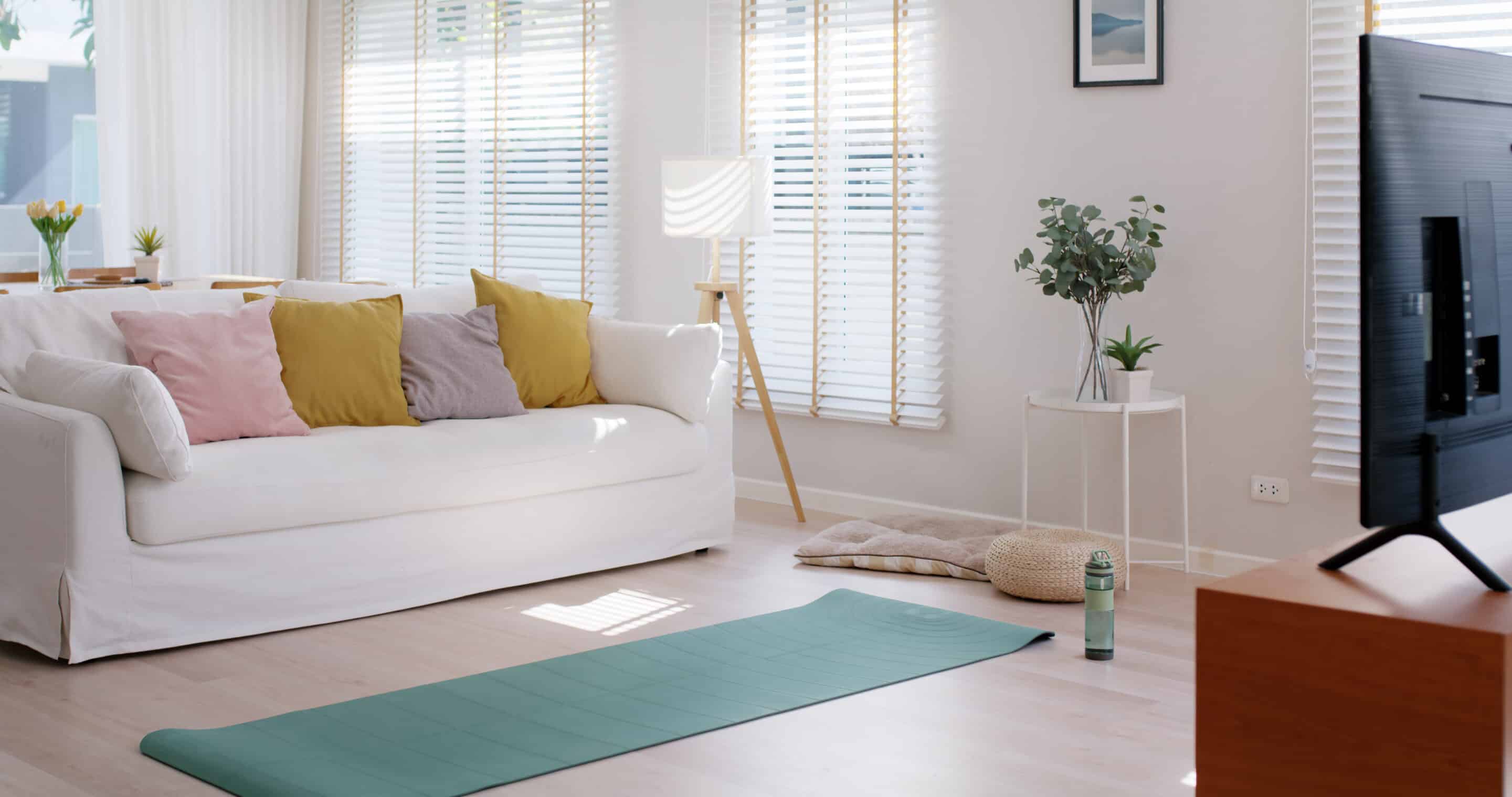 Empty room in calm relax warm morning with modern cozy white sofa couch and sun light on blinds shades window with beautiful wood floor. Prepare workout online gym at home in minimal style. Motor and Blinds