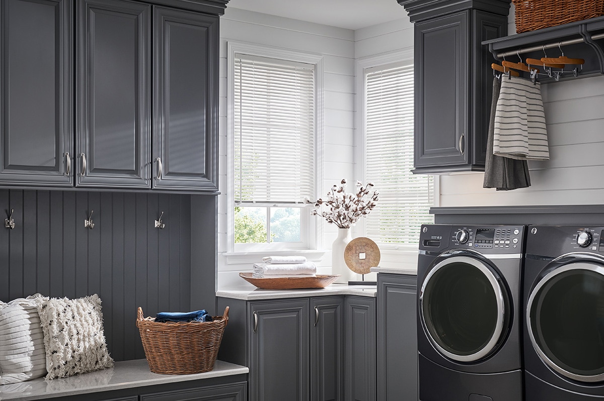 Aluminum blinds filtering in light in a sleek laundry room.