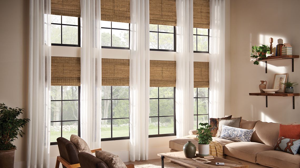 8 newly installed woven wooden shades halfway open filtering in light into a living room.