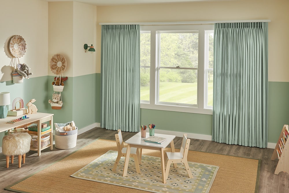 Green drapery partially covering the windows in a play room.